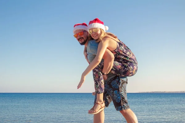 Couple avec des chapeaux de Noël et des lunettes de soleil sur la plage de la mer — Photo