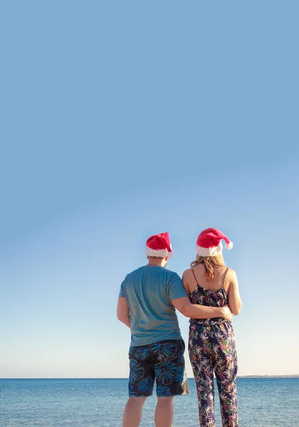 Homme étreignant femme dans des chapeaux de Noël et regardant la plage de la mer — Photo