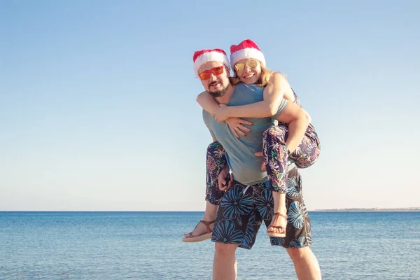 Avec des chapeaux de Noël et des lunettes de soleil sur la plage de la mer — Photo