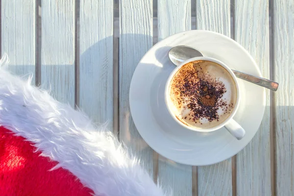 kahve fincanı ve beyaz ahşap bir masa Noel kutlamaları Santas şapka
