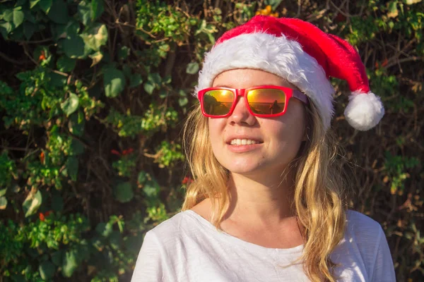 Portrait d'une jolie jeune femme en chapeau et lunettes de soleil du Père Noël. tonique . — Photo