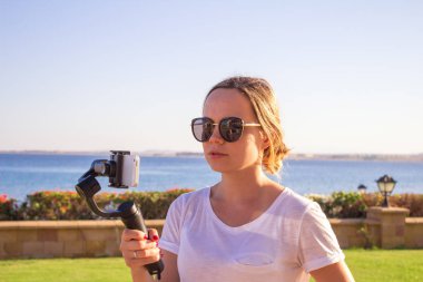 Blogger video kız. İşleç gimbal stabilize kavrama eylem kamera ile. Mutlu genç kadın 4 k görüntüleri olayda açık vuruyor