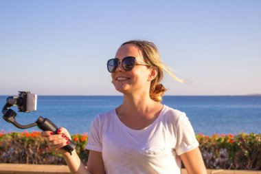 Günbatımı seyahat, blogger yapma gimbal ve cep telefonu, günbatımı sahil sahne ile video video çekimi kadın