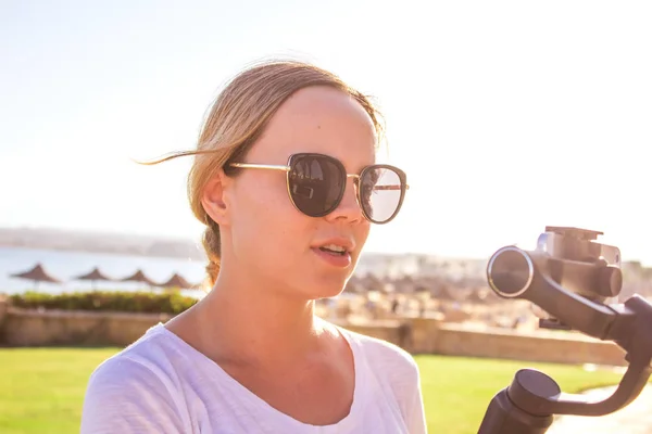 Video blogger meisje. Operator met actiecamera op gestabiliseerde grip met gimbal. Gelukkig jonge vrouw scheuten 4k beelden op gebeurtenis buiten Rechtenvrije Stockfoto's