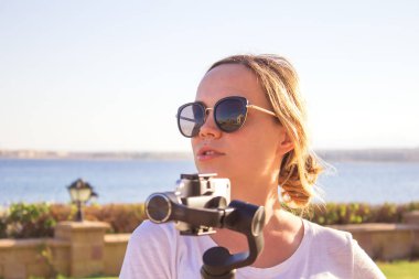 Genç çekici adam steadycam gimbal ve bir telefon kullanarak seyahat video filmler.