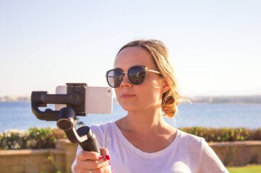 Blogger video kız. İşleç gimbal stabilize kavrama eylem kamera ile. Mutlu genç kadın 4 k görüntüleri olayda açık vuruyor