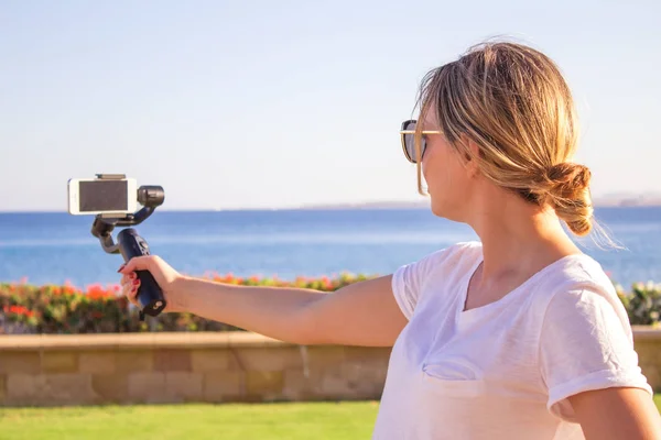 Blogger video kız. İşleç gimbal stabilize kavrama eylem kamera ile. Mutlu genç kadın 4 k görüntüleri olayda açık vuruyor