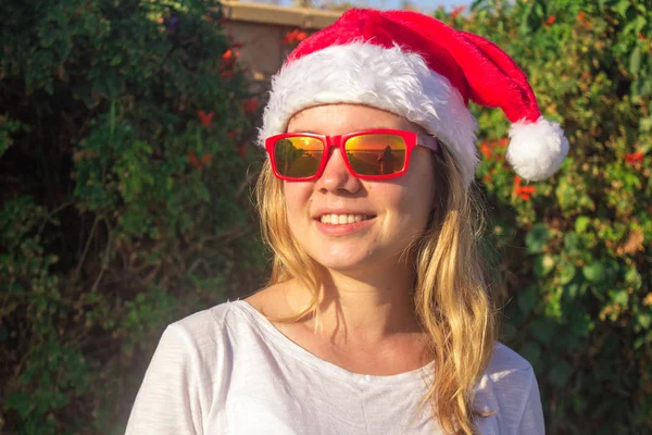 Portrait d'une jolie jeune femme en chapeau et lunettes de soleil du Père Noël. tonique . — Photo