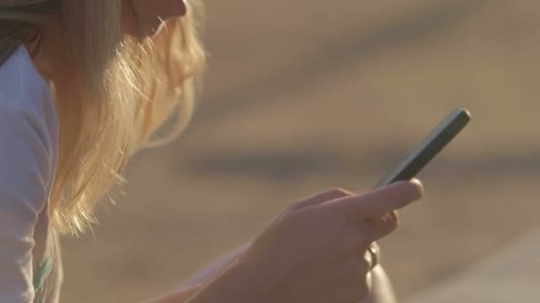 Το κορίτσι με το κινητό στην παραλία το καλοκαίρι Ταξιδέψτε στη θάλασσα. κοντινό πλάνο — Αρχείο Βίντεο