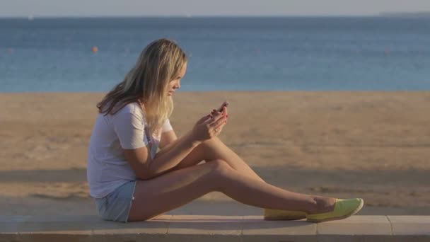 Chica con teléfono móvil en la playa en el viaje de verano en el mar — Vídeo de stock