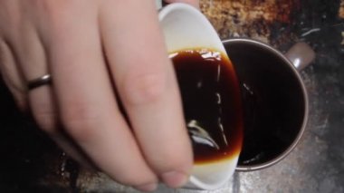 adam kapuçino hazırlar. siyah kahve ve süt dökülen