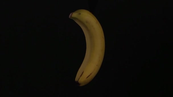 Yellow banana is spinning on a black background in isolation — Stock Video