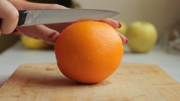 Женщина режет апельсин на деревянной доске. чтобы приготовить свежий смузи — стоковое видео
