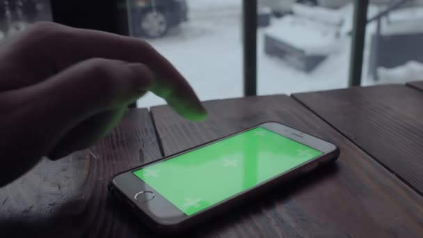 Man handen typen op groen scherm mobiele telefoon op houten tafel in café. — Stockvideo