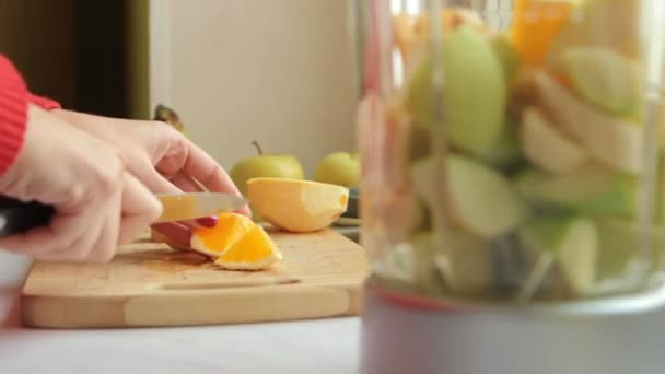 Βάζοντας τα φρούτα στο μπλέντερ. Κόψτε το πορτοκάλι. — Αρχείο Βίντεο