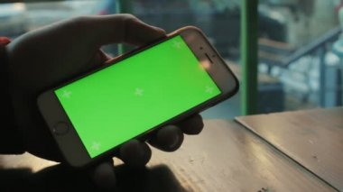 Ahşap masa, bir kafede bir siyah ceketli adamı telefon ile yeşil ekran kullanır.