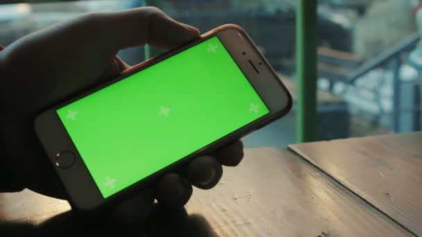 Een man een café aan de houten tafel maakt gebruik van de telefoon met groen scherm — Stockvideo