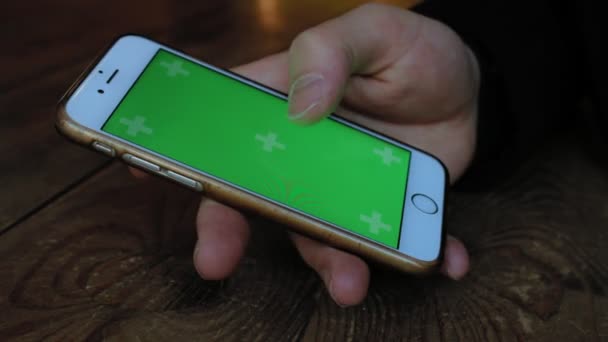 Un hombre un café en la mesa de madera utiliza el teléfono con pantalla verde — Vídeos de Stock