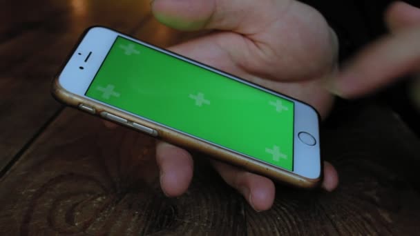 Un hombre un café en la mesa de madera utiliza el teléfono con pantalla verde — Vídeos de Stock