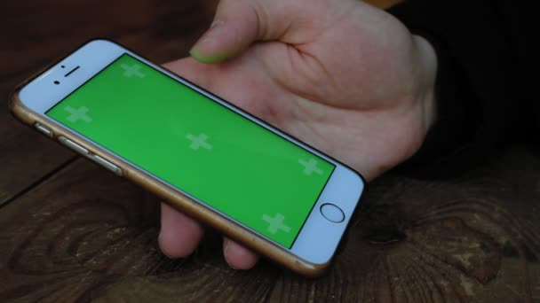 Een man een café aan de houten tafel maakt gebruik van de telefoon met groen scherm — Stockvideo