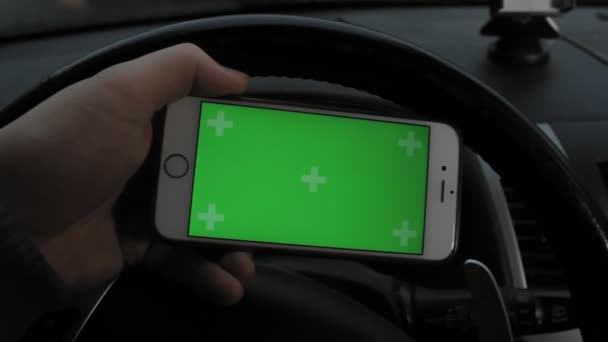 Mano del hombre que sostiene el teléfono inteligente móvil con la pantalla verde de la llave del croma en coche — Vídeos de Stock