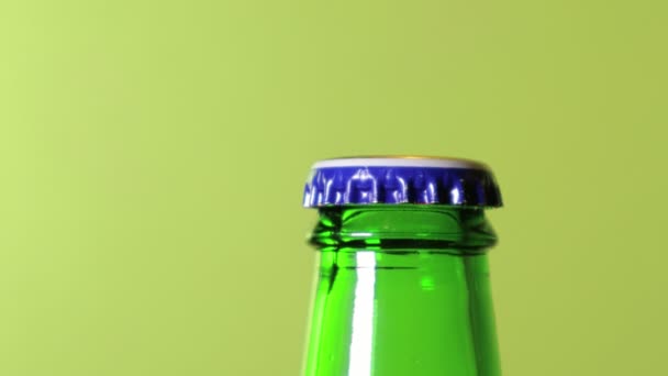 緑の背景にビールの緑のボトルを開き手. — ストック動画