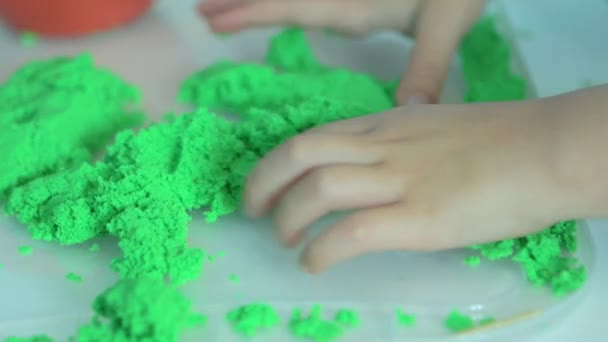 Close-up van schattige 3 jaar baby jongen handen spelen met kinetische zand thuis. — Stockvideo