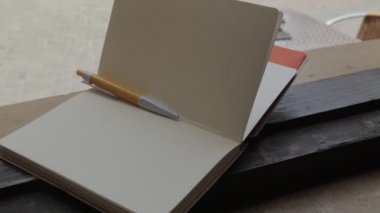 Rüzgar pencerenin pervazında duran boş bir not defterinin sayfalarını çevirir .