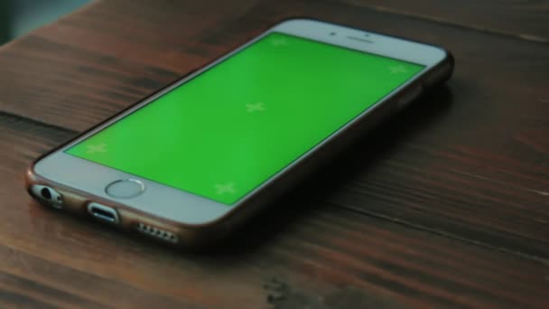 Teléfono blanco con una pantalla verde está en una mesa de madera marrón oscuro en un café — Vídeos de Stock