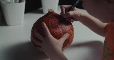 Cadılar bayramı için balkabağı süsleyen ve boyayan bir çocuk.