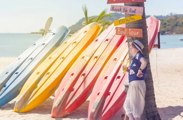カラフルなカヤックの近くにカクテルと帽子でビーチで成熟した女性 — ストック写真