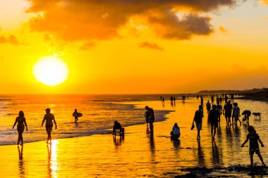 Bali, Endonezya plajında bir günbatımı arka planda insanların siluetleri