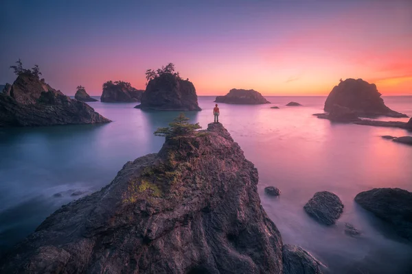 Bu seastack üstüne ayakta ve Oregon Coast gün batımını izlemek bir insanın bir fotoğraf olduğunu.