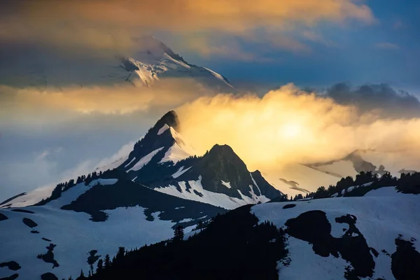 Schneebedeckter Berg und Wolken im Licht der untergehenden Sonne — Stockfoto