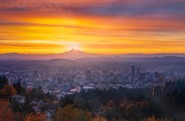 Portland şehir merkezinde sonbahar yeşillikleri ince sisli, parlak gündoğumu ve renkli bulutlarla.