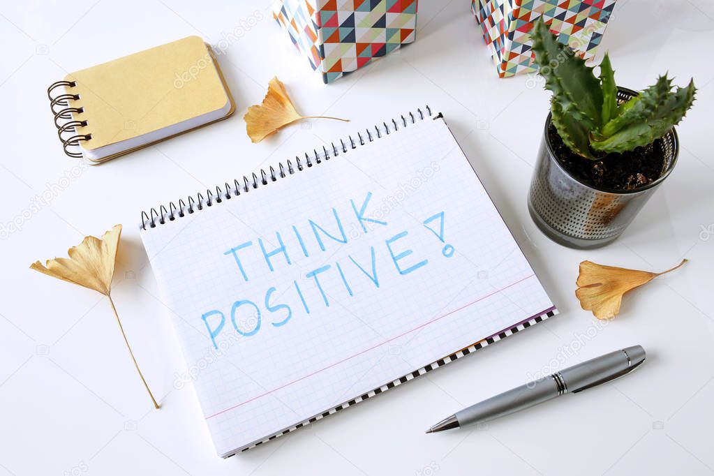 think positive written in a notebook on white table