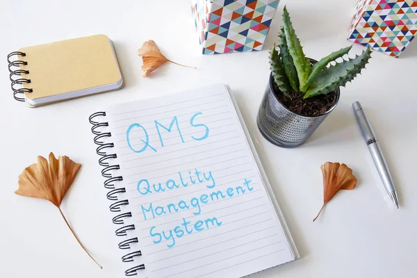 QMS Quality management system written in a notebook on white tab