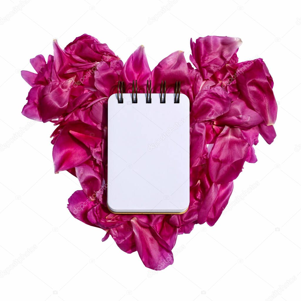 notebook on pink heart made from peony petals 