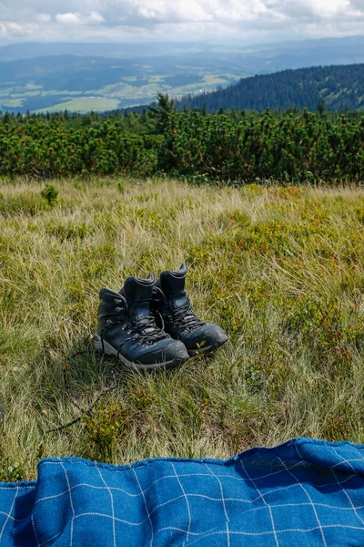 Dağ çayırında yürüyüş botları ve battaniye