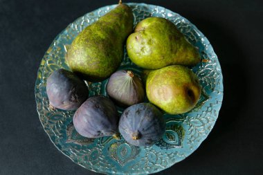 Gümüş bir tabakta yeşil armutlar ve incir meyveleri