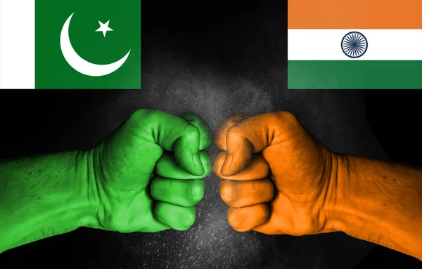 Conflict between India and Pakistan, male fists with flags painted on skin isolated on black background - governments conflict concept