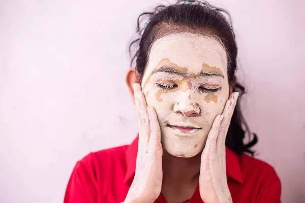 Young brunette girl message ayurvedic natural hearbal cosmetic facial mask applied over her face. multani mitti/fuller earth clay Pack copy space