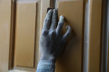 Hintli marangozun kirli eli zımpara kağıdı ve ahşap kaplama konseptiyle ev mobilyalarını bitiriyor..