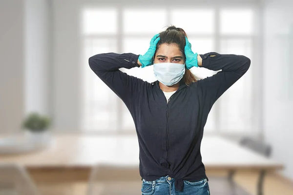 Tired confused frustrated indian girl wearing surgical mask and gloves feeling headache and sick new normal life style, indoor room, copy space