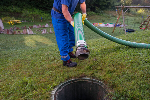 Emptying household septic tank. Cleaning and unblocking clogged drain with vacuum pipe.