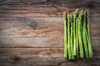 Ahşap bir arka planda bir sürü taze kuşkonmaz. Boşluğu kopyala