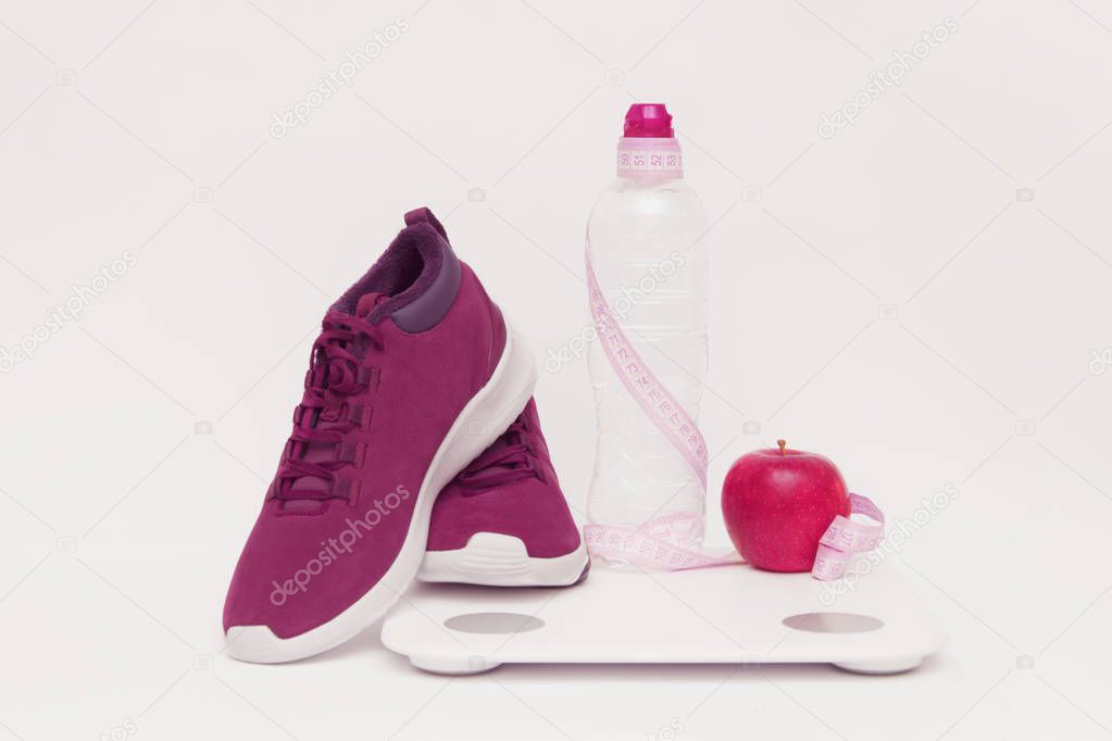 Sports equipment, apple and scales a bottle   water on a toned background.