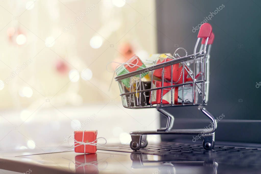 Concept of Christmas online shopping. A cart with gifts on a laptop