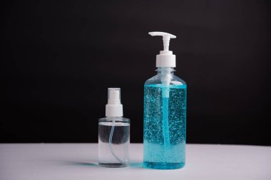 Plastik dezenfektan alkol jeli pompası ve sprey şişesi. Siyah arka planda çekilen koronavirüs virüs stüdyosunun el hijyeni önlenmesi için.