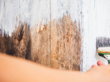 DIY, yakın plan kadın eli boya fırçası kullanıyor ya da eski ahşap rengi ahşap masa üzerine beyaz renge boyuyor